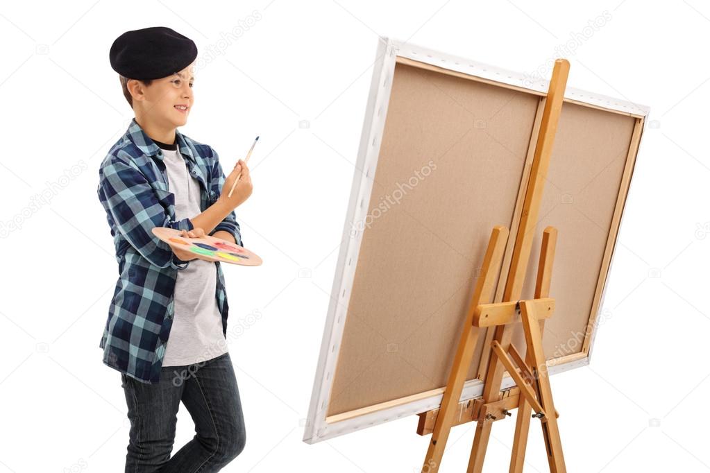 Boy looking at canvas with paintbrush and palette