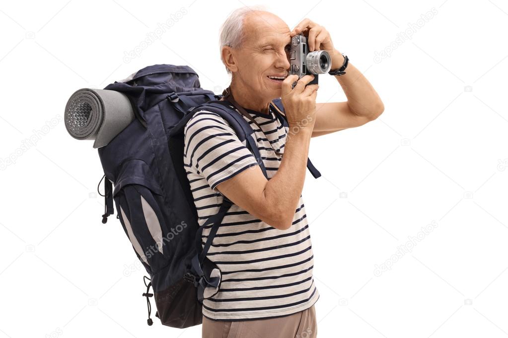 Elderly male hiker taking a picture with a camera