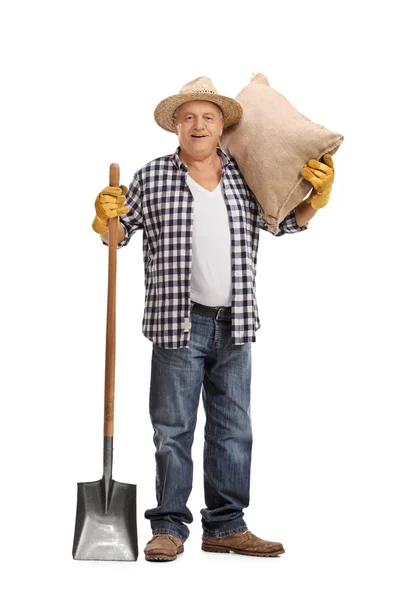 Senior boer poseren met een zak en een schop — Stockfoto