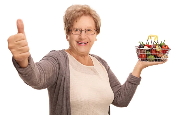 Mature woman holding a small basket and thumb up — Stock Photo, Image