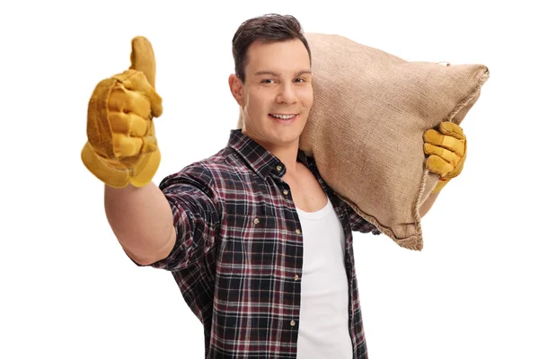 Male farmer holding burlap sack and giving thumb up — Stock Photo, Image