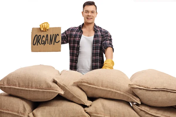 Agricultor atrás de pilha de sacos e sinal que diz orgânico — Fotografia de Stock