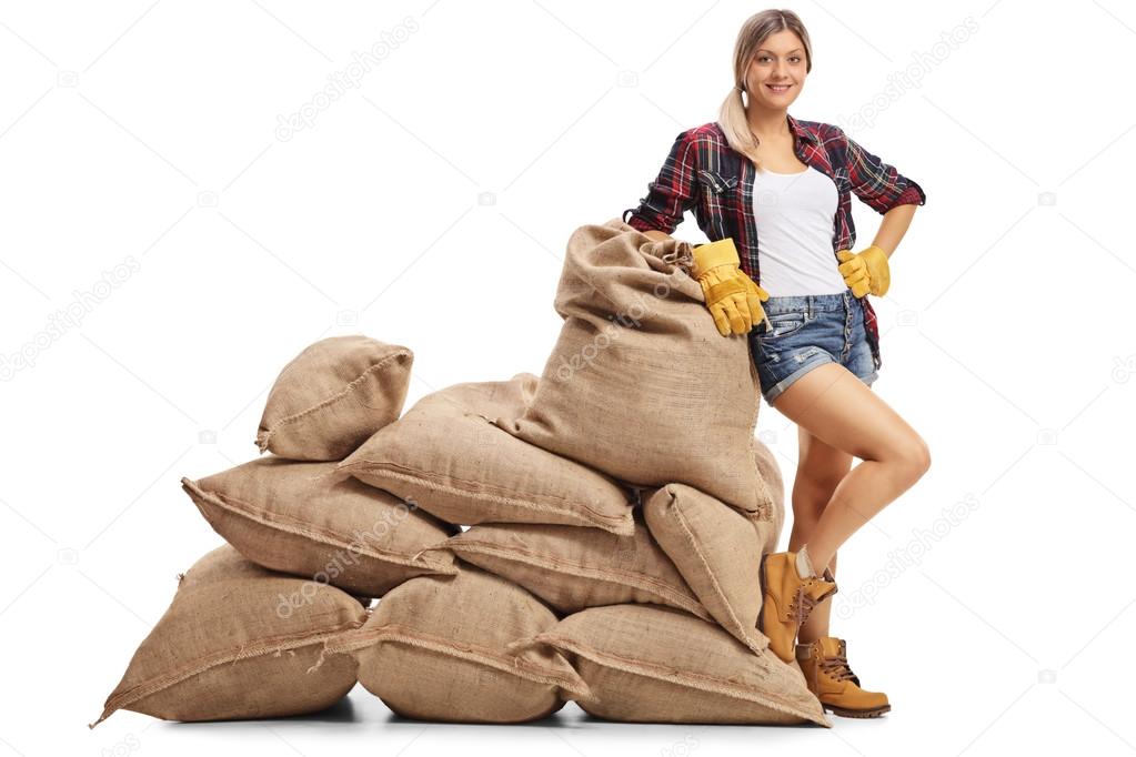 Female farmer leaning on a pile of burlap sacks