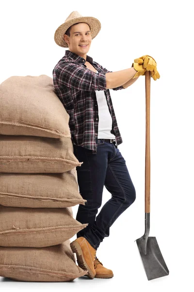 Agricultural worker leaning on pile of burlap sacks — Stock fotografie
