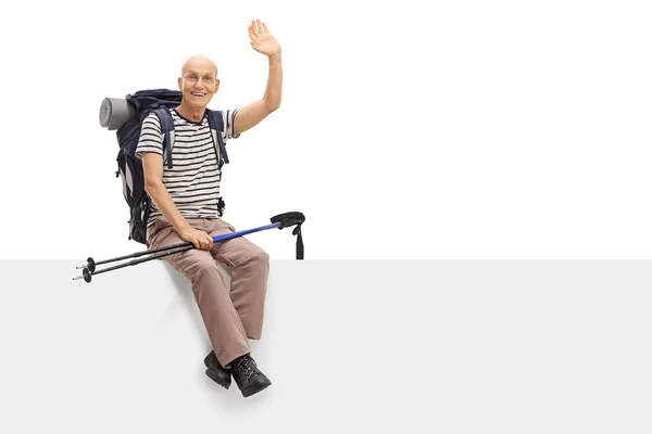 Mature hiker sitting on a panel and waving — Stock Photo, Image