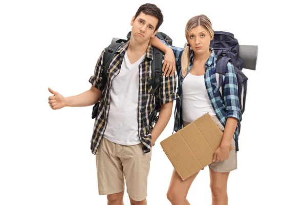 Sad hikers holding a blank cardboard sign and hitchhiking — Stock fotografie