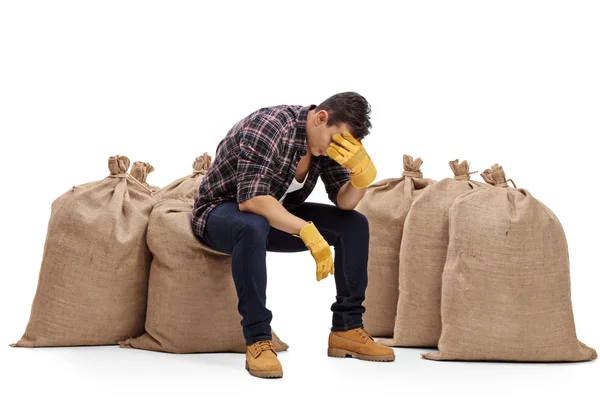 Agricultor deprimido sentado en un saco de arpillera —  Fotos de Stock