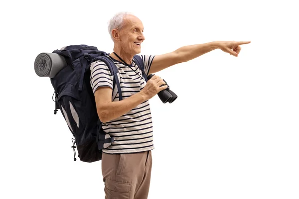 Volwassen wandelaar holding verrekijkers en wijzen in de verte — Stockfoto