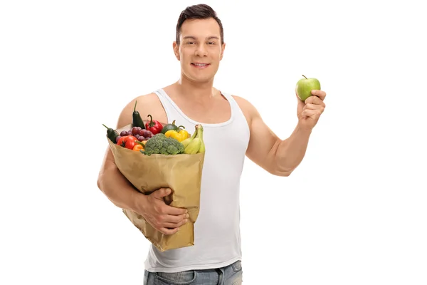 Man holding a shopping bag and an apple — Stock Photo, Image