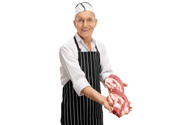 Elderly butcher offering beef steaks — Stock Photo, Image
