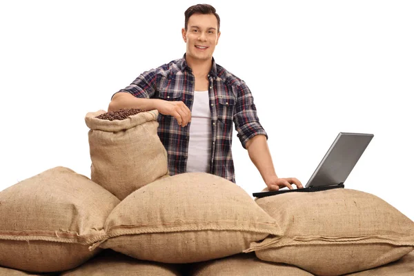 Trabalhador agrícola posando com sacos de serapilheira e laptop — Fotografia de Stock