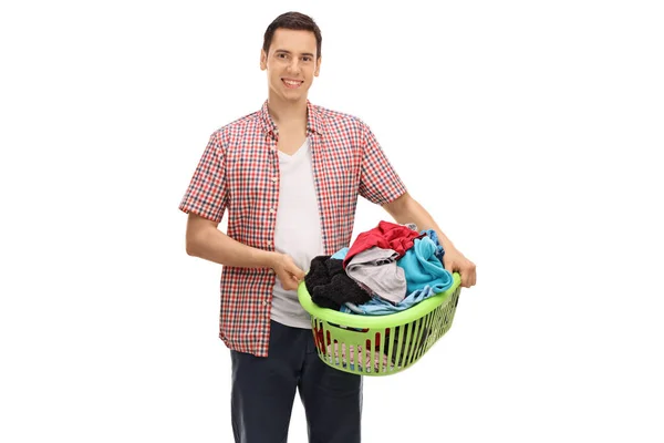 Jovem segurando uma cesta de roupa cheia de roupas — Fotografia de Stock