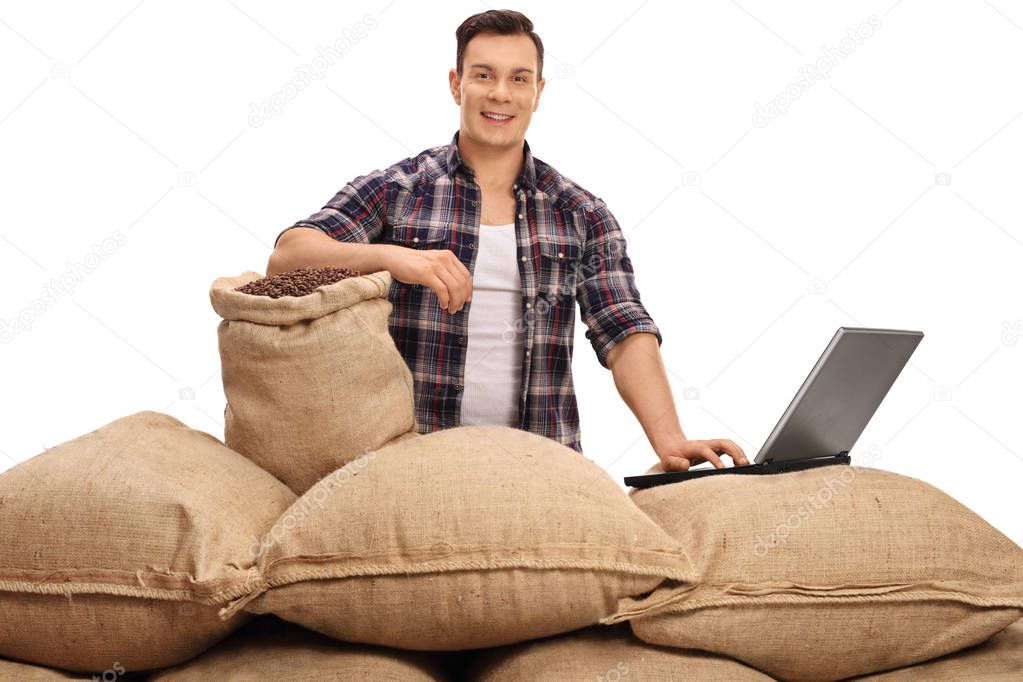 agricultural worker posing with burlap sacks and laptop