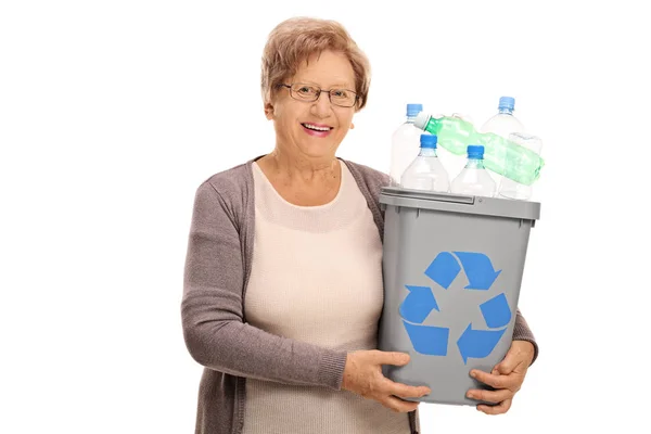 Glad mogen kvinna som håller papperskorgen full av plastflaskor — Stockfoto