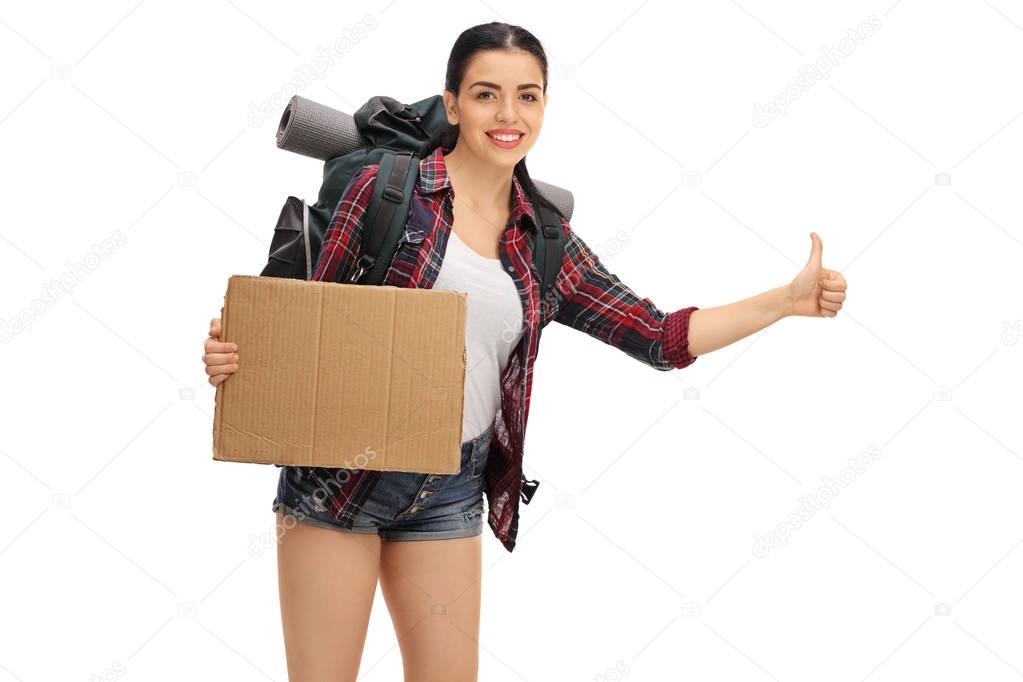 Female hiker hitchhiking and holding blank cardboard sign
