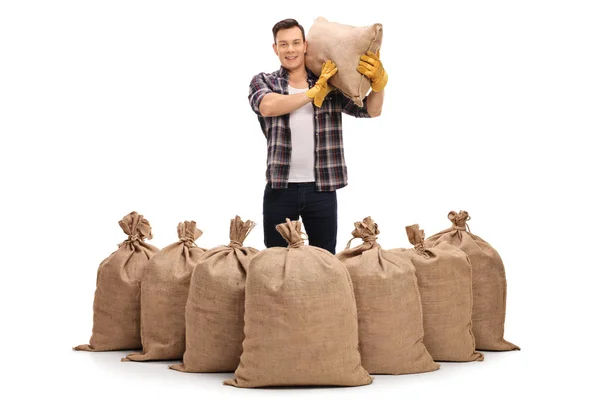 Jordbruks-arbetare bakom säckväv säckar och hålla en säck — Stockfoto
