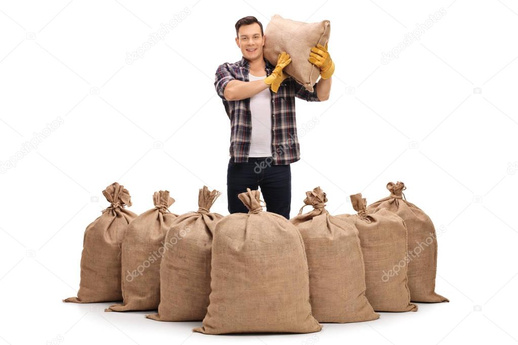 Agricultural worker behind burlap sacks and holding a sack
