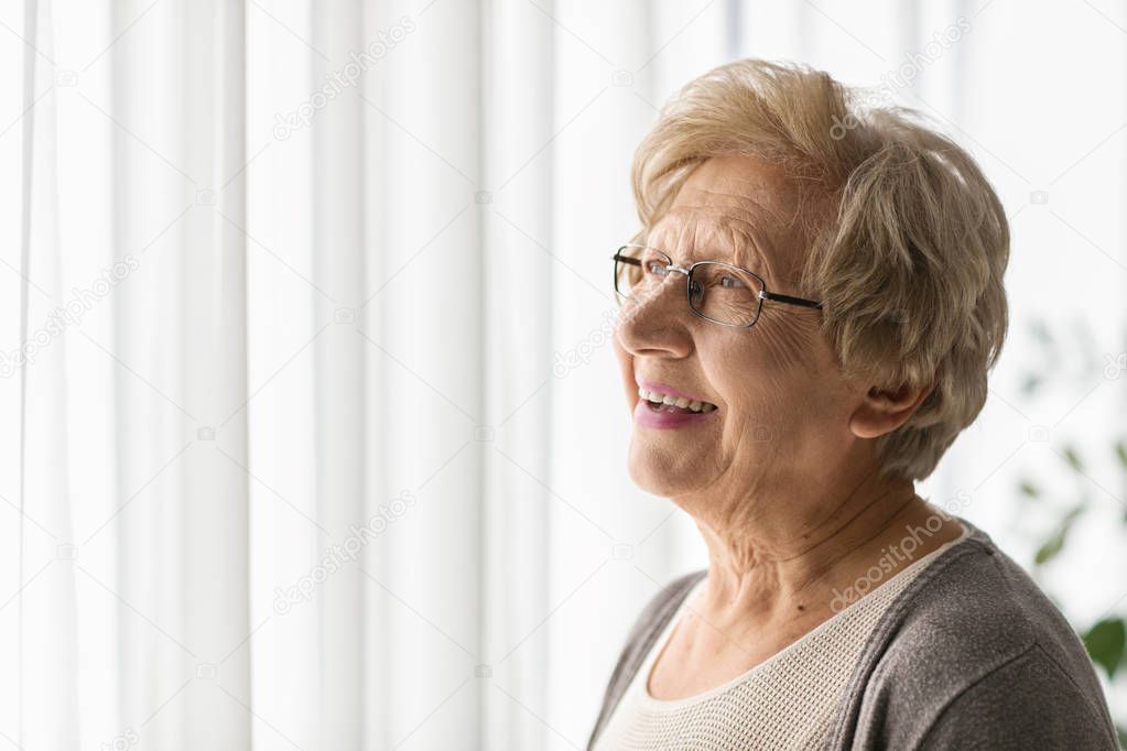 Elderly woman looking through a window