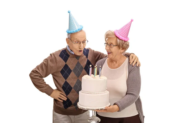 Kobieta trzyma tort urodzinowy i człowieka dmuchanie — Zdjęcie stockowe