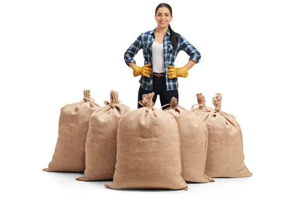 Agricultor feminino em pé atrás de sacos de serapilheira — Fotografia de Stock