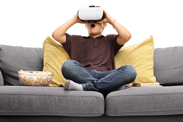 Menino em um sofá usando óculos de realidade virtual — Fotografia de Stock