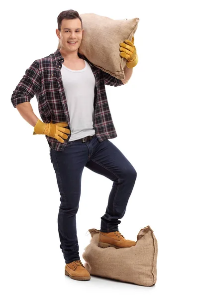 Farmer with a burlap sack on his shoulder and under his foot — Stock Photo, Image