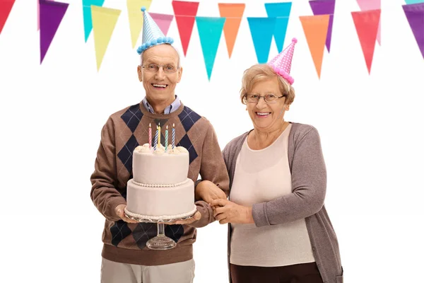 Glückliche Senioren mit Party-Hüten und Geburtstagstorte — Stockfoto
