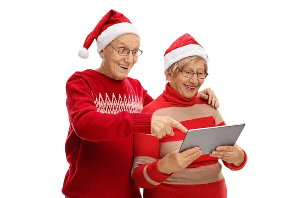 Seniorzy z Santa kapelusze patrząc na tablet — Zdjęcie stockowe