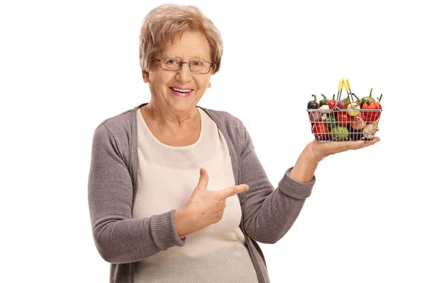 Mujer sosteniendo una pequeña cesta de la compra y señalando — Foto de Stock