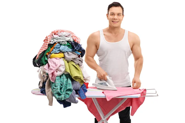 Joyful guy ironing a pile of clothes — Stock Photo, Image