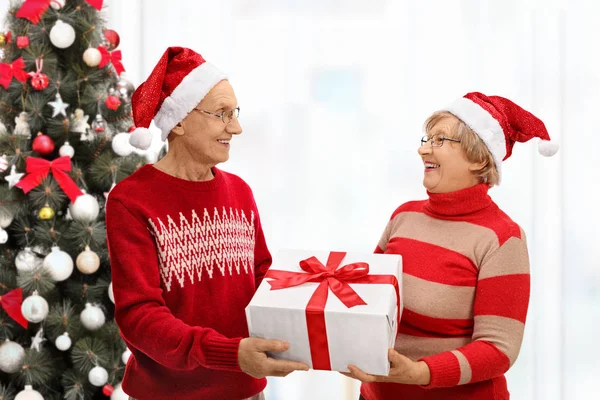 Senior dengan topi Natal saling menghadiahi — Stok Foto