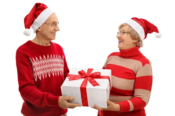 Senioren met Santa hoeden gifting van elkaar — Stockfoto