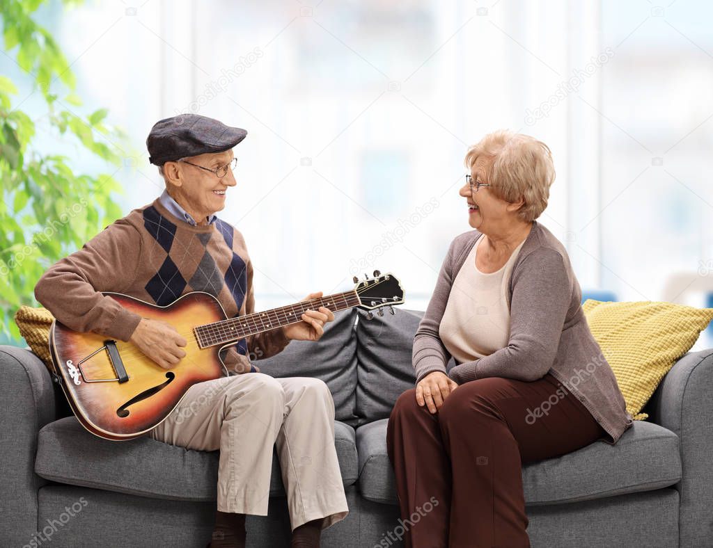 Elderly man playing a guitar to an elderly