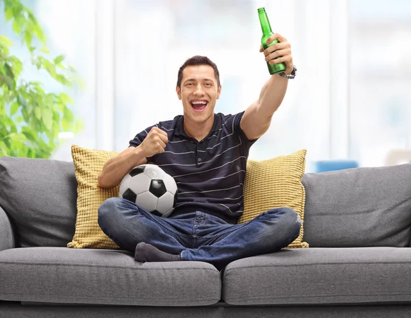 サッカーを見て、ビールを持って、ソファの上の男 — ストック写真