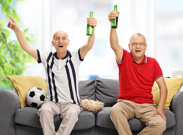 Senioren gezeten op een bank voetbal kijken en juichen — Stockfoto