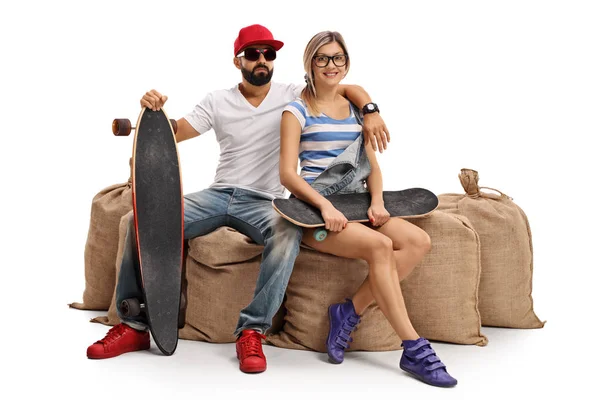 Skateurs avec un longboard et un skateboard assis sur un sac en toile de jute — Photo