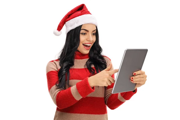Vrolijke vrouw met een kerstmuts op zoek naar een tablet — Stockfoto