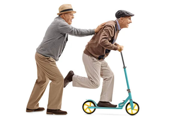 Mature man pushing another man on a scooter — Stock Photo, Image