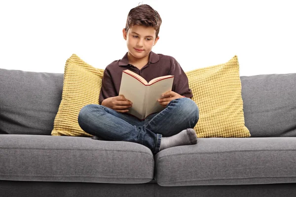Jongen zit op een bank en lezen van een boek — Stockfoto