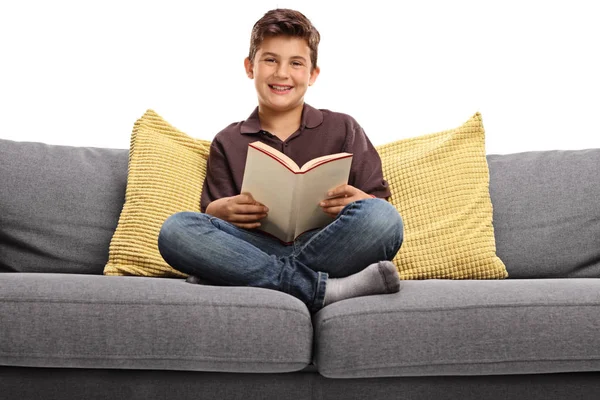 Happy boy on sofa holding a book — Stock Photo, Image