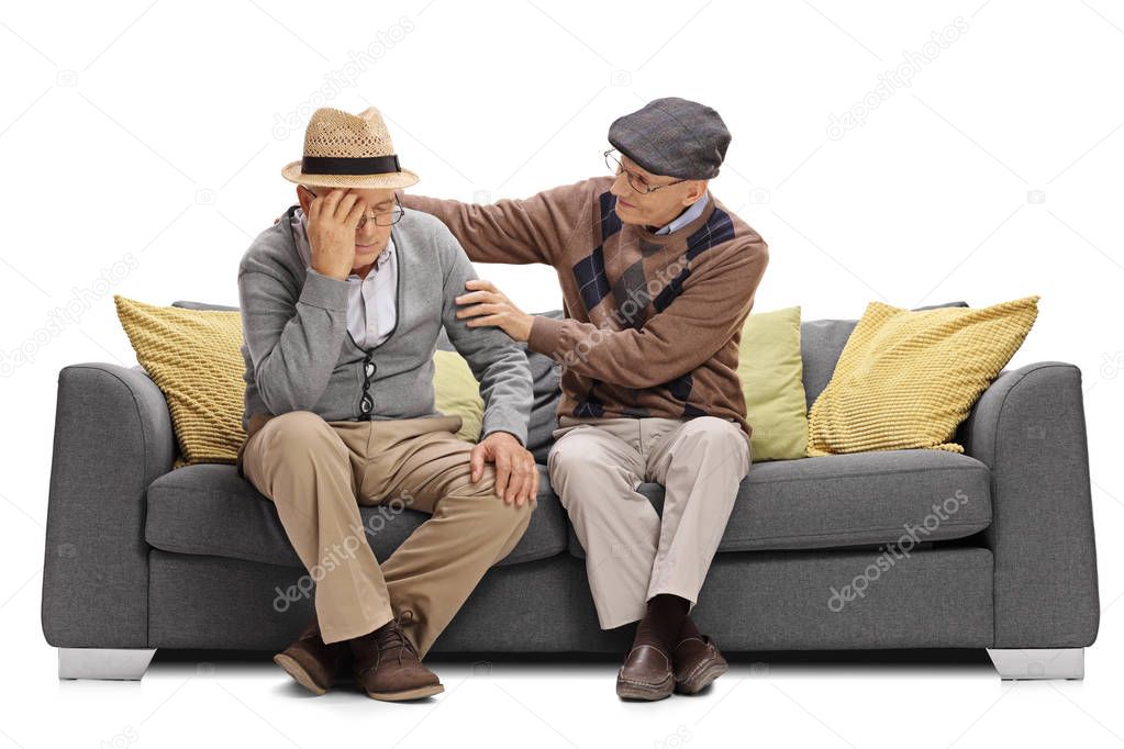 Elderly man sitting on a sofa and comforting another man