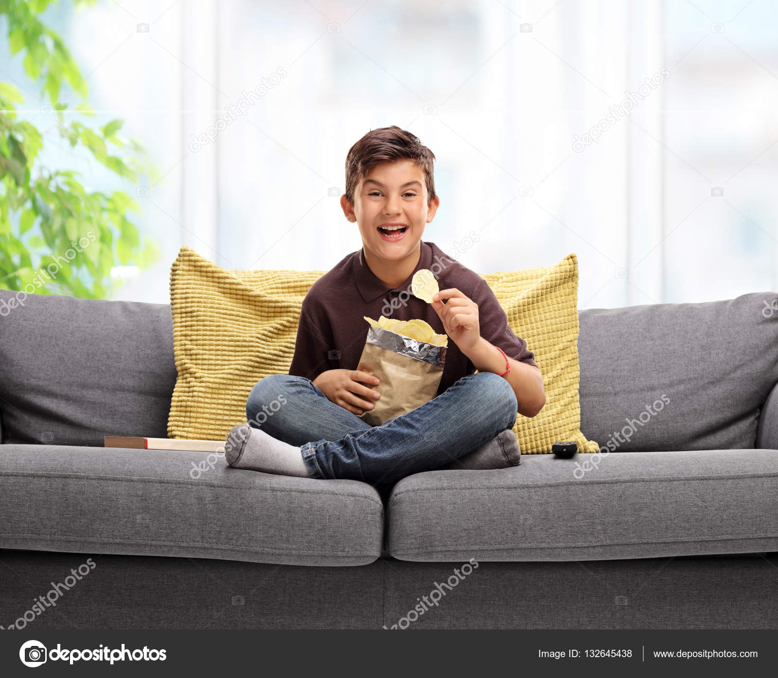 Boy Sitting On A Sofa And Eating Potato Chips Stock Photo Boy Sitting On A Sofa And Eating Potato Chips Stock Photo