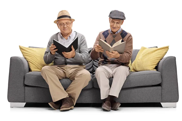 Idosos sentados em um sofá e lendo livros — Fotografia de Stock