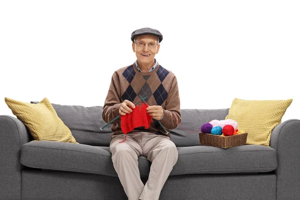 Старший сидит на диване и вяжет — стоковое фото