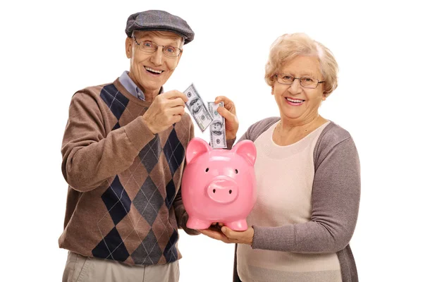 Пожилые люди вкладывают деньги в копилку — стоковое фото
