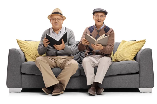 Hombres maduros con libros sentados en un sofá —  Fotos de Stock
