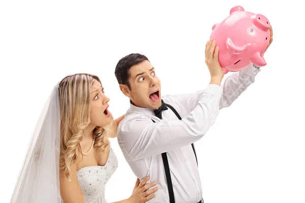 Shocked newlywed couple shaking an empty piggybank — Stock Photo, Image