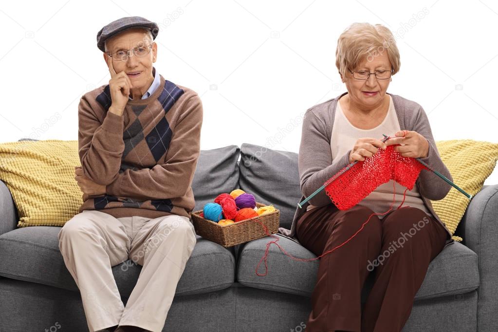man on a sofa next to an woman knitting