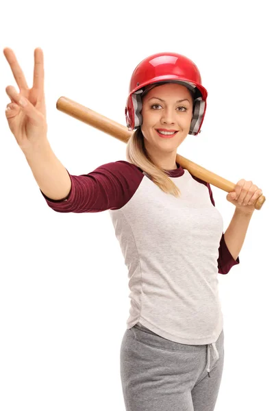 Vrouw met een honkbalknuppel en een helm waardoor een vredesteken — Stockfoto