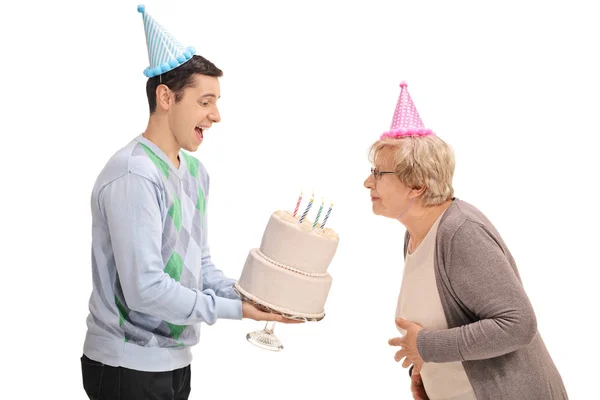 Мужчина держит торт на день рождения с женщиной, задувающей свечи — стоковое фото